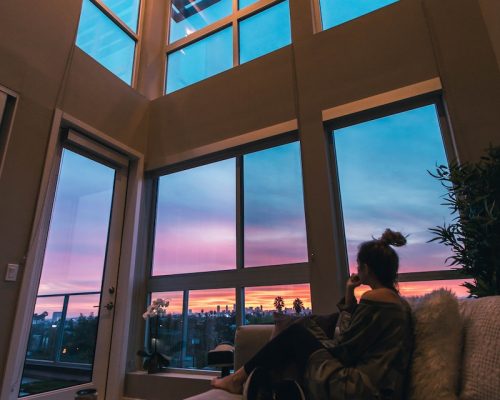 a person sitting on a couch looking out a window